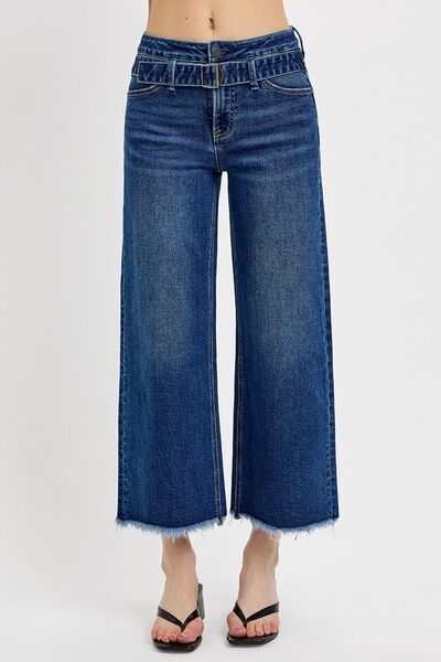 Wide-leg jeans with raw hem and buckle detail.