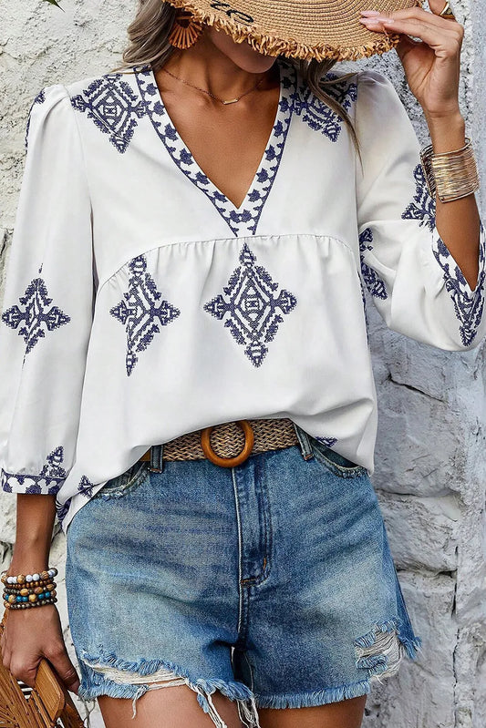 Printed V-neck three-quarter sleeve blouse, polyester, no stretch, worn with denim shorts.