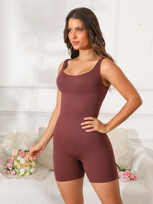 Woman wearing a scoop neck wide strap active romper in a room with floral decor.