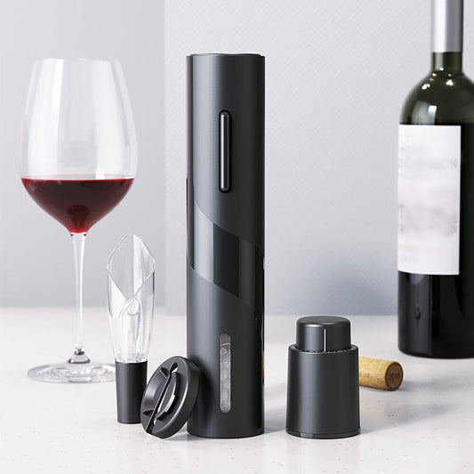 One-click Electric Wine Bottle Opener with accessories, including foil cutter, on a table with a glass of red wine and a corked bottle.